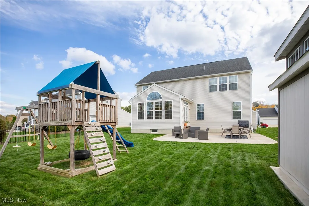 Rear view of house featuring a playground and a patio