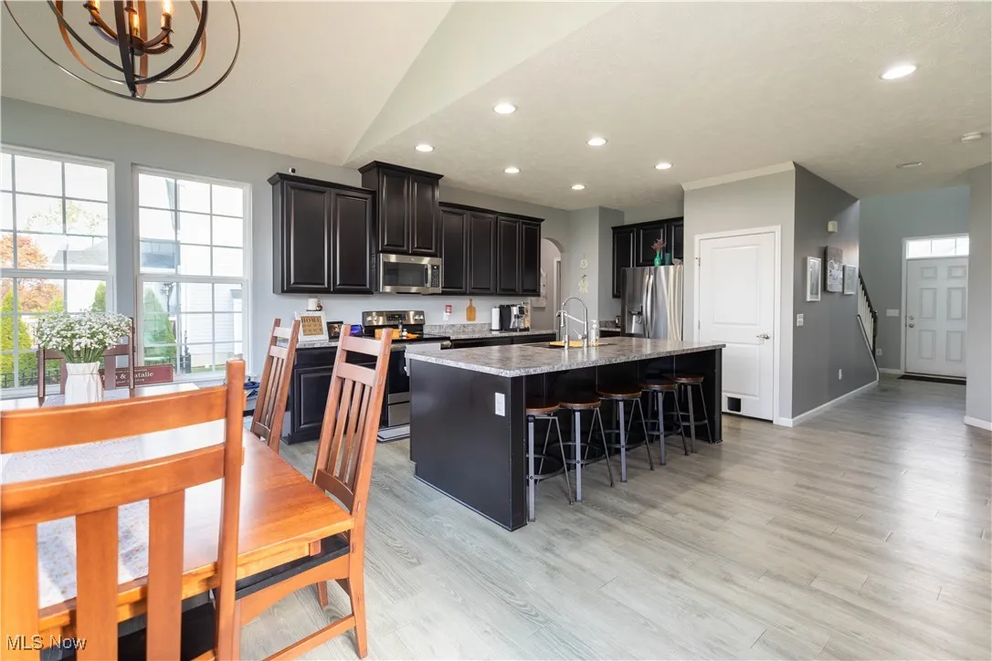 Kitchen featuring a kitchen island with sink, appliances with stainless steel finishes, recessed lighting, a kitchen bar, and light wood-style floors