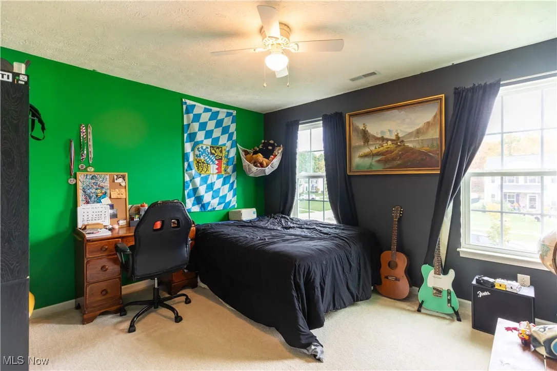 Bedroom featuring carpet flooring, a textured ceiling, and ceiling fan