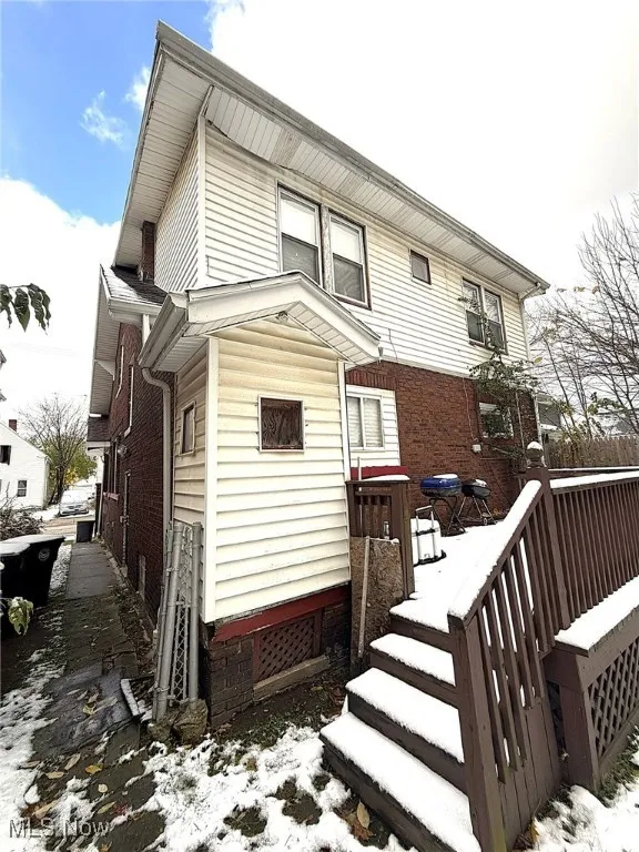 Snow covered back of property with brick siding