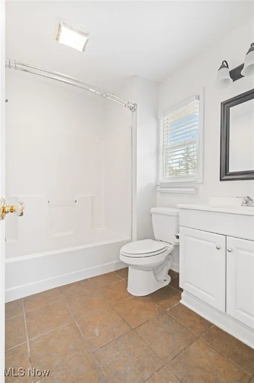 Full bathroom with vanity, shower / bath combination, and dark tile patterned floors