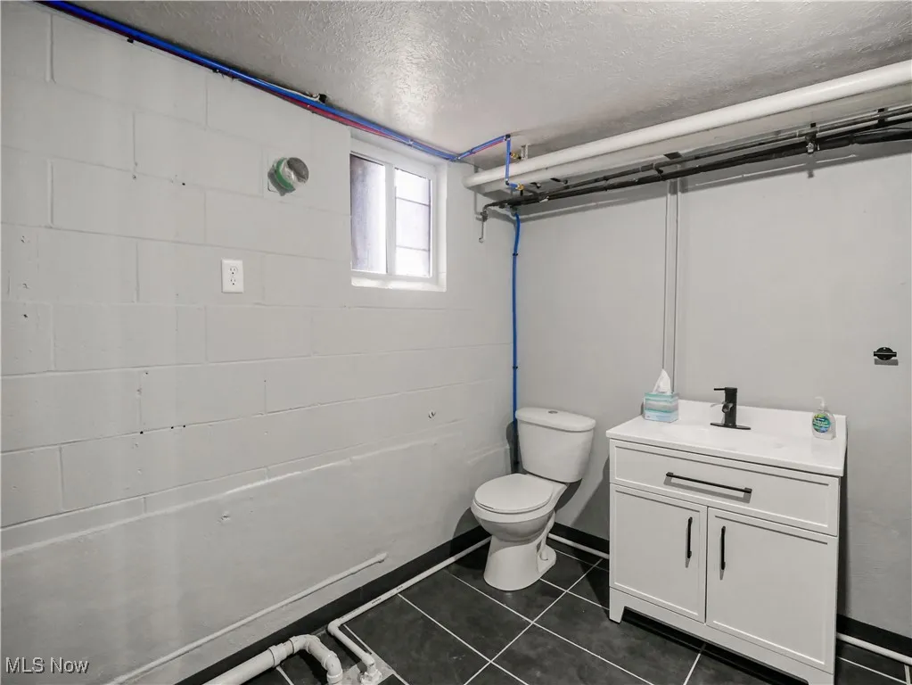 Bathroom with vanity, a textured ceiling, and dark tile patterned floors