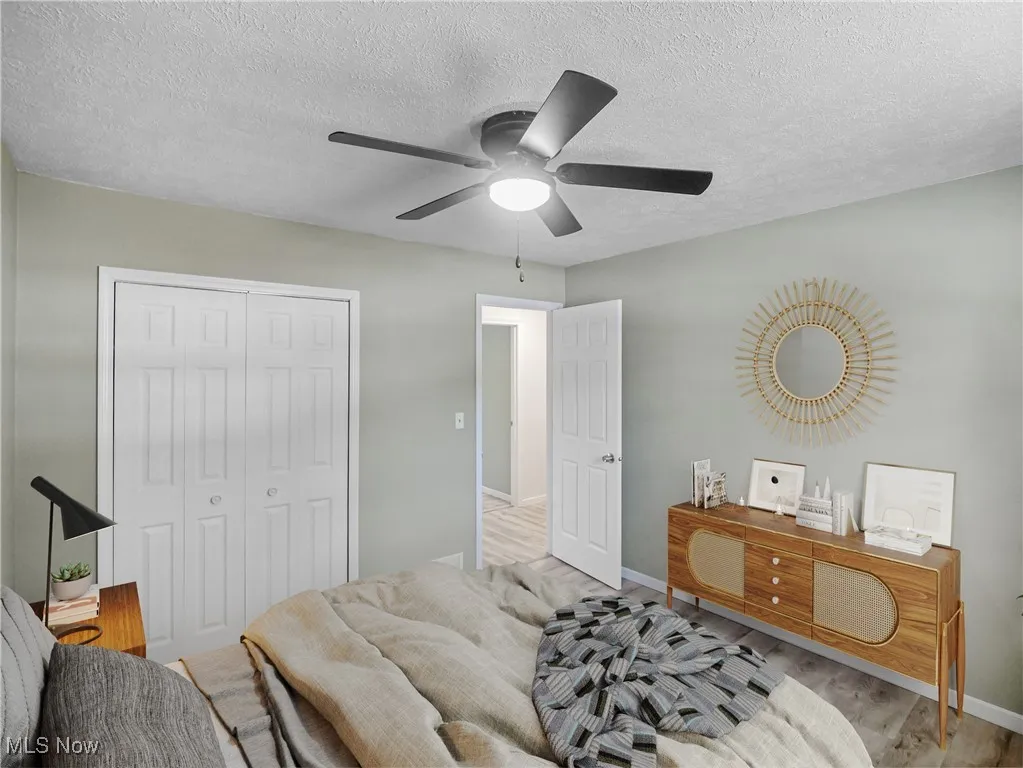 Bedroom with wood finished floors, a textured ceiling, a closet, and a ceiling fan VIRTUALLY STAGED*