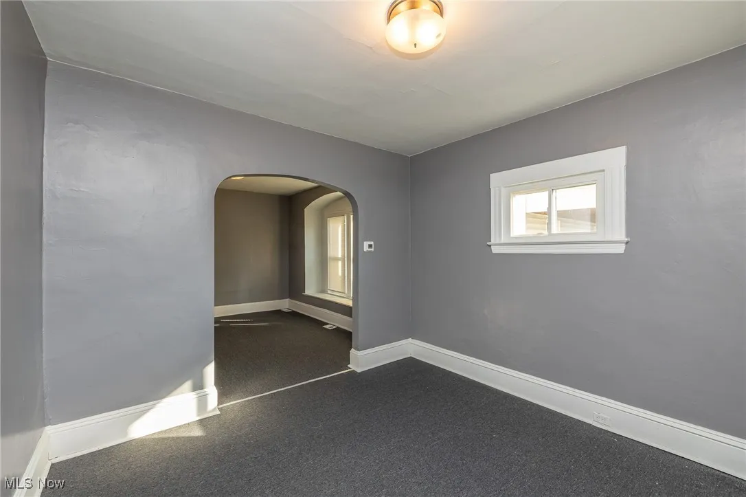 Spare room with arched walkways and dark carpet