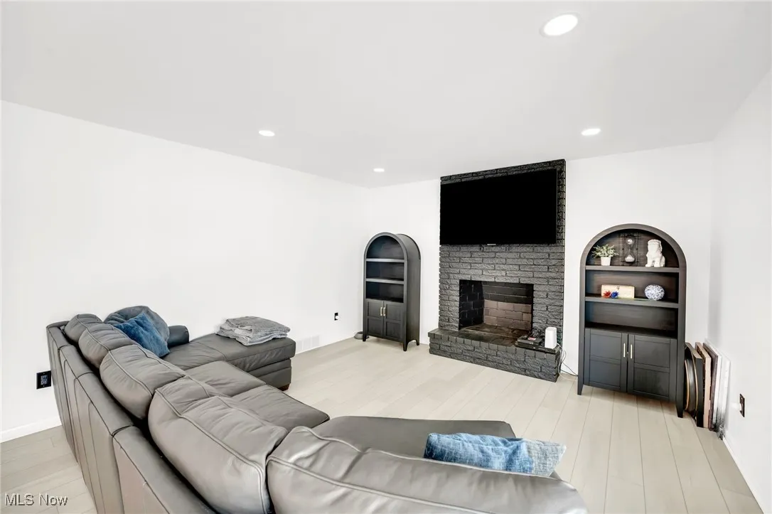 Living room featuring recessed lighting, light wood-type flooring, and a fireplace
