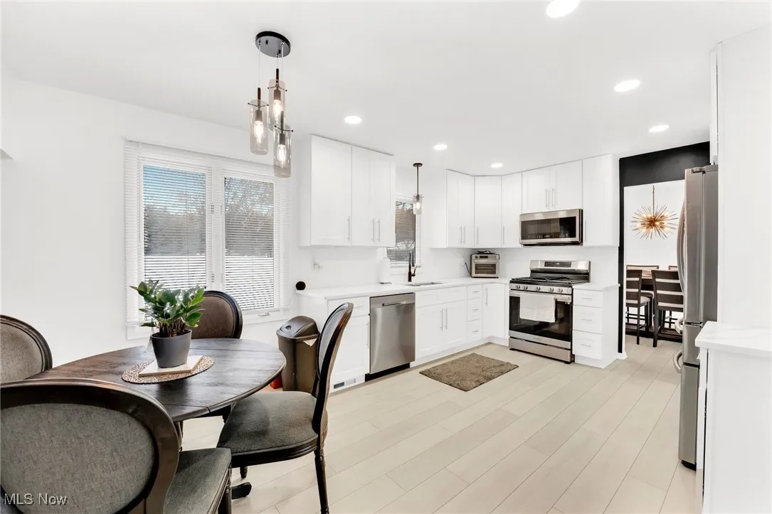 Kitchen with appliances with stainless steel finishes, hanging light fixtures, white cabinets, recessed lighting, and light wood-style flooring