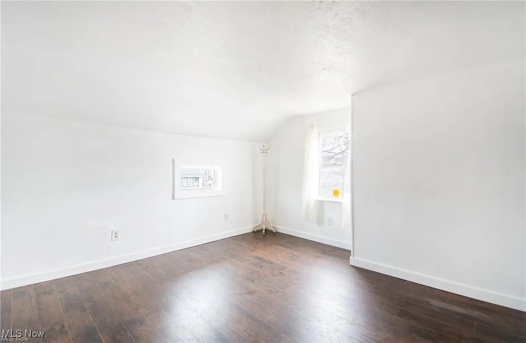 Additional living space with dark wood finished floors, a textured ceiling, and vaulted ceiling