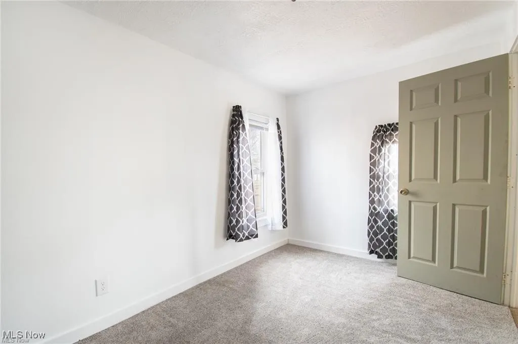 Carpeted spare room featuring baseboards and a textured ceiling