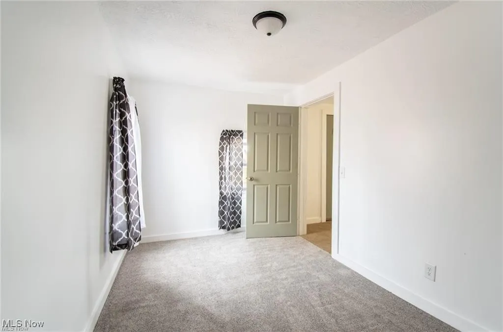 Unfurnished room featuring light carpet and baseboards