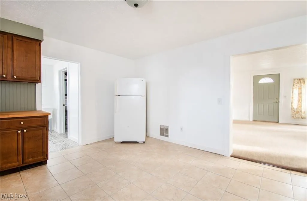 Unfurnished room featuring light tile patterned flooring and light carpet