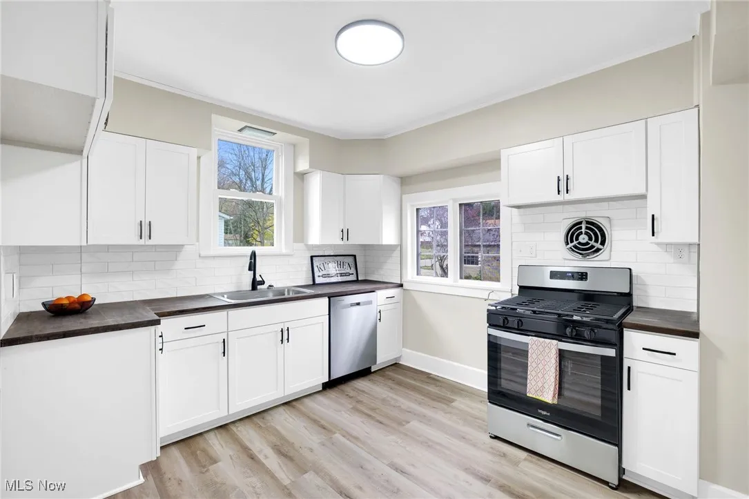 Kitchen featuring stainless steel appliances, backsplash, plenty of natural light, and white cabinetry