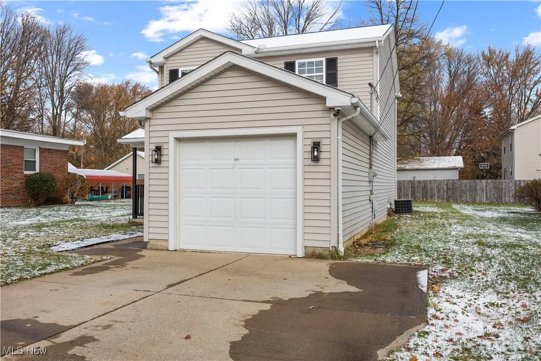 Snow covered garage featuring driveway