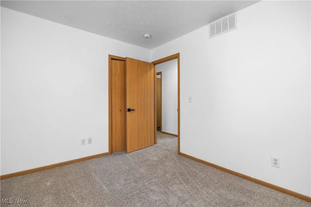 Empty room with a textured ceiling and light colored carpet