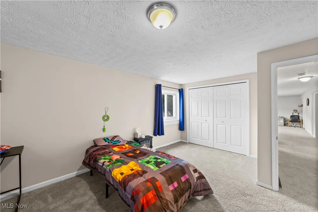 Bedroom with light colored carpet, a textured ceiling, and a closet