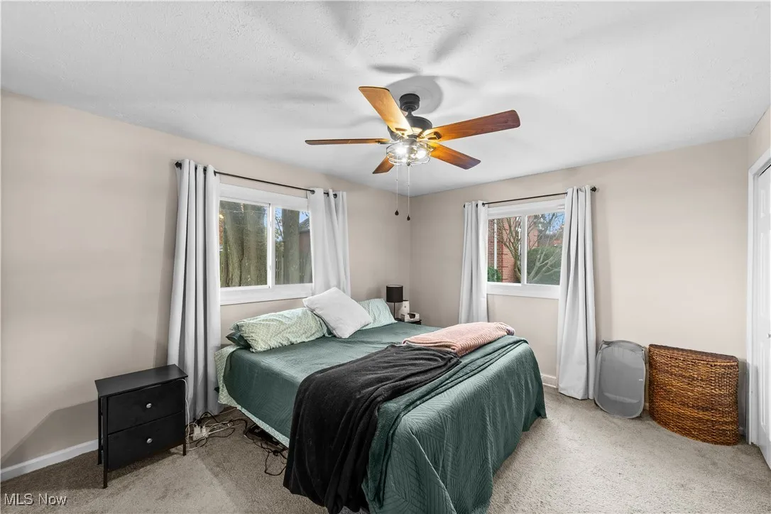 Bedroom with light carpet, a ceiling fan, and a textured ceiling