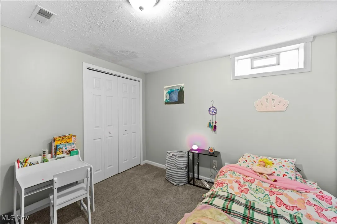 Bedroom featuring dark carpet, a closet, and a textured ceiling
