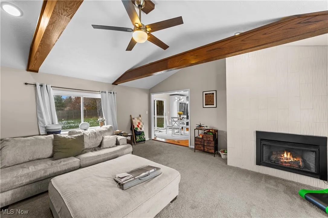 Living room with carpet floors, a fireplace, and a ceiling fan