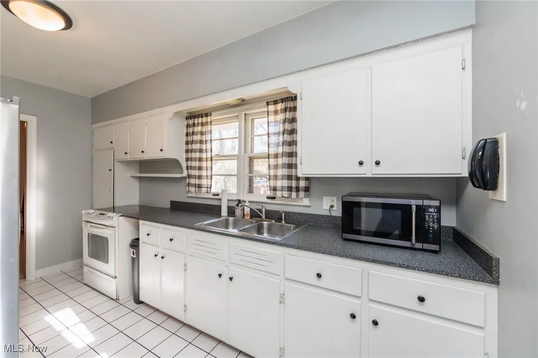 Kitchen with dark countertops, appliances with stainless steel finishes, and white cabinets