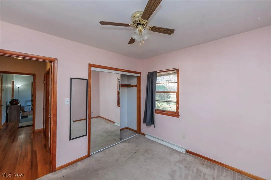 Unfurnished bedroom featuring a baseboard heating unit, ceiling fan, a closet, and carpet floors