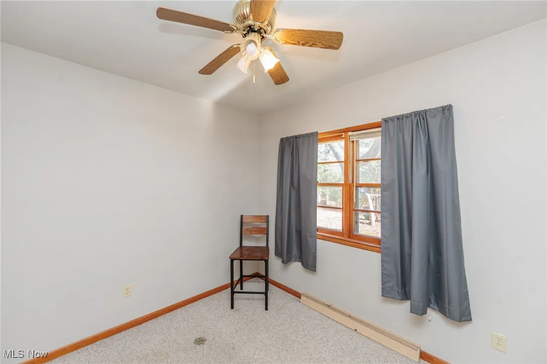 Carpeted empty room with baseboard heating and ceiling fan