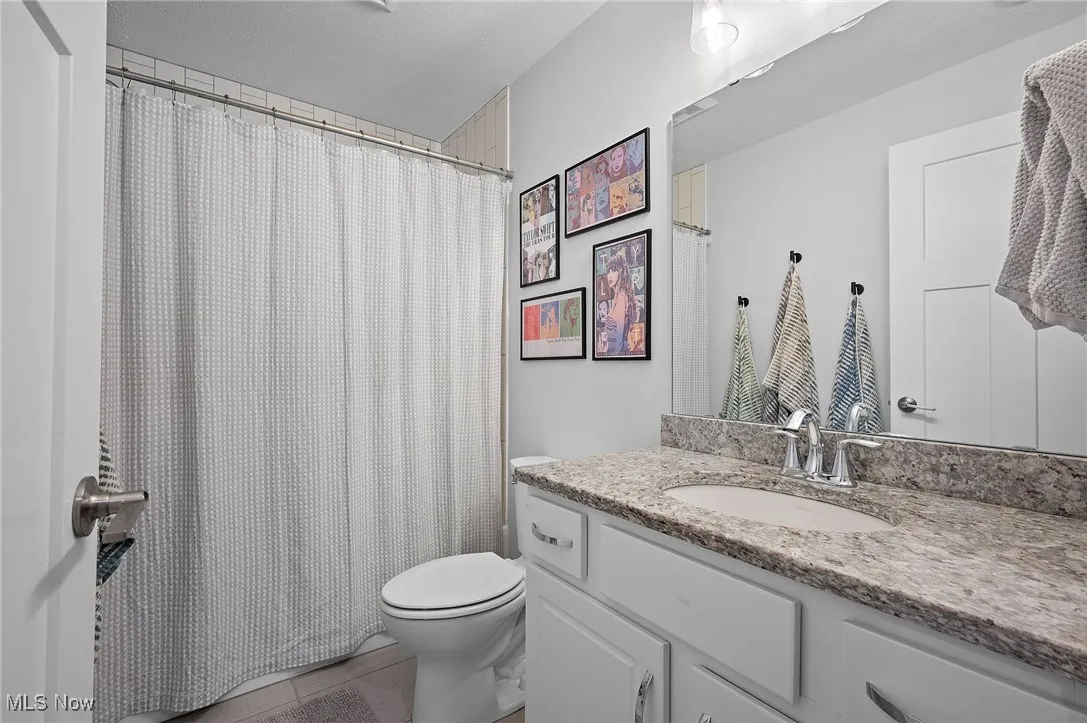Full bath featuring a shower with curtain, vanity, and light tile patterned floors