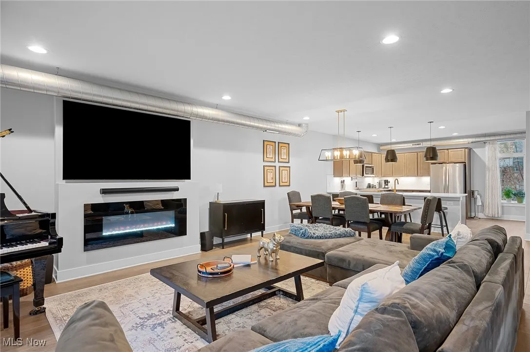 Living area with recessed lighting, light wood finished floors, and a glass covered fireplace