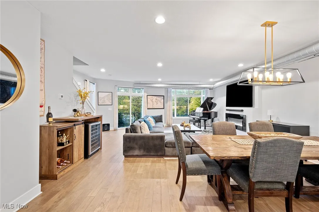 Dining area featuring a glass covered fireplace, light wood finished floors, recessed lighting, and wine cooler