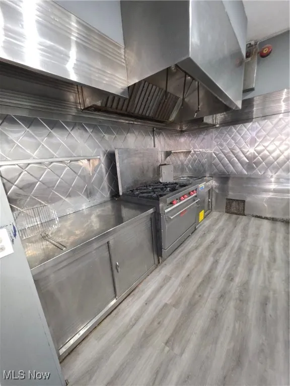 Kitchen featuring exhaust hood, stainless steel range, and gray cabinets