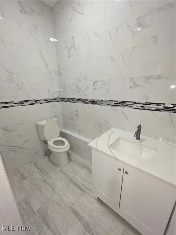 Bathroom featuring tile walls, vanity, and a tub