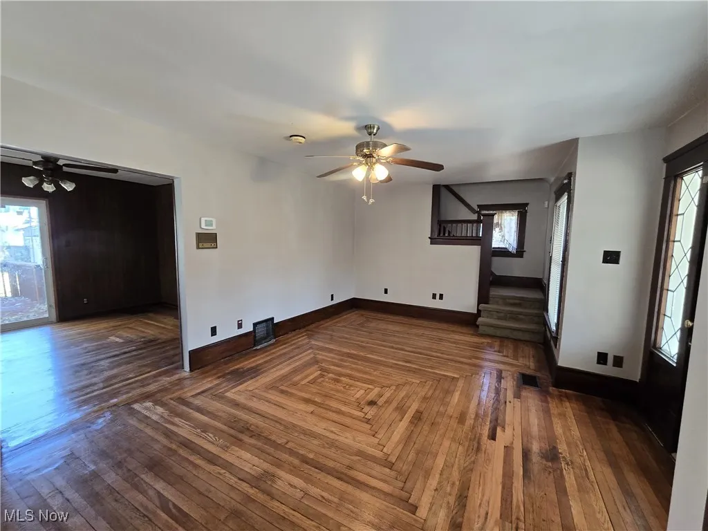 Unfurnished living room with plenty of natural light, a ceiling fan, and stairs