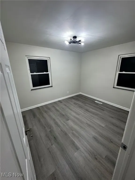 Empty room with dark wood finished floors and baseboards