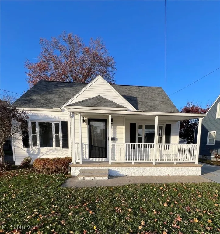 Bungalow-style house with a shingled roof, a porch, and a front yard