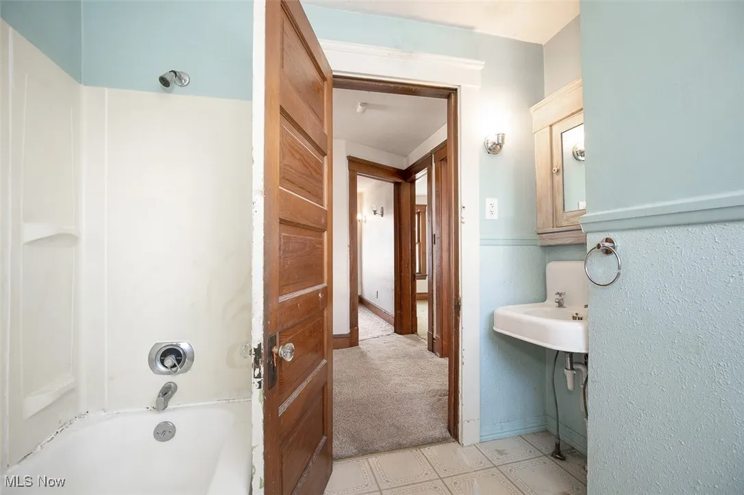Bathroom featuring shower / tub combination and light colored carpet