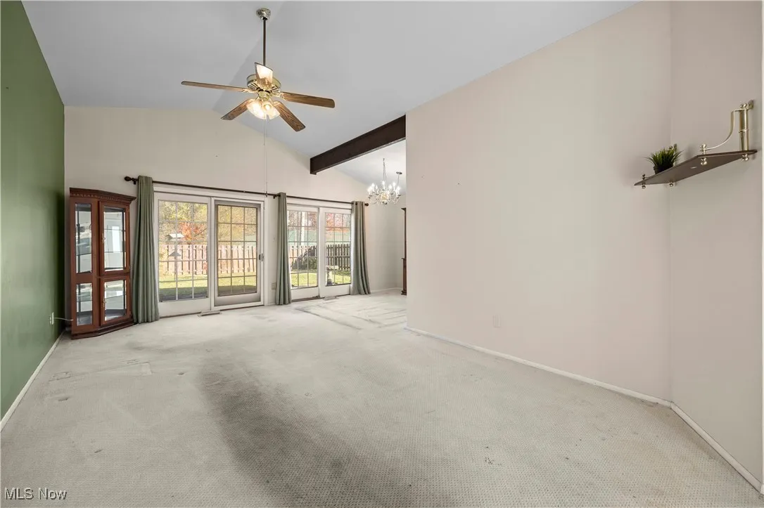 Spare room with carpet flooring, a chandelier, high vaulted ceiling, and a ceiling fan