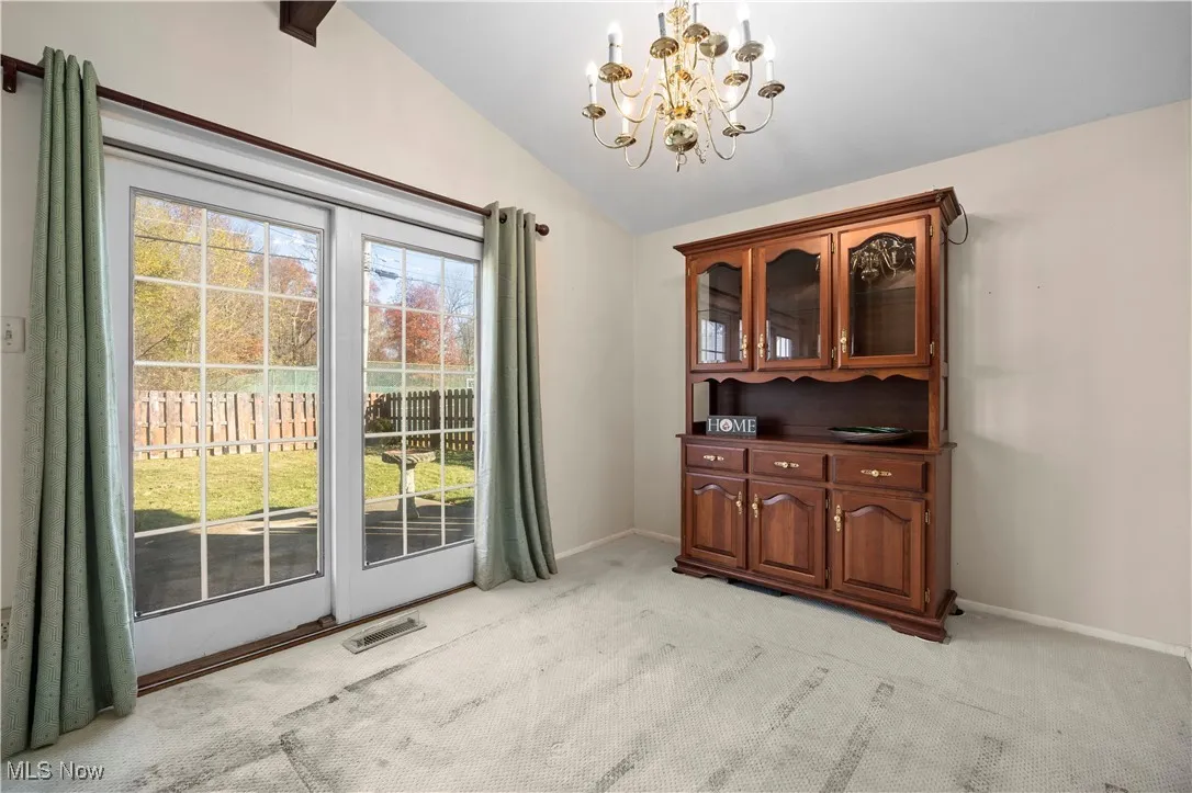 Dining space featuring a chandelier, light colored carpet, and lofted ceiling