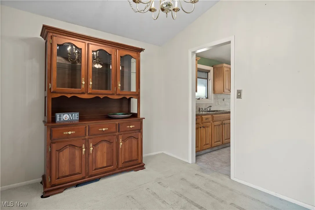 Hall featuring light colored carpet, a chandelier, and lofted ceiling