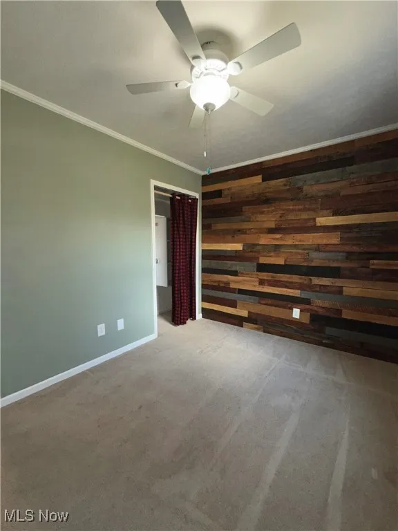 Bedroom with ornamental molding, carpet flooring, and wooden walls