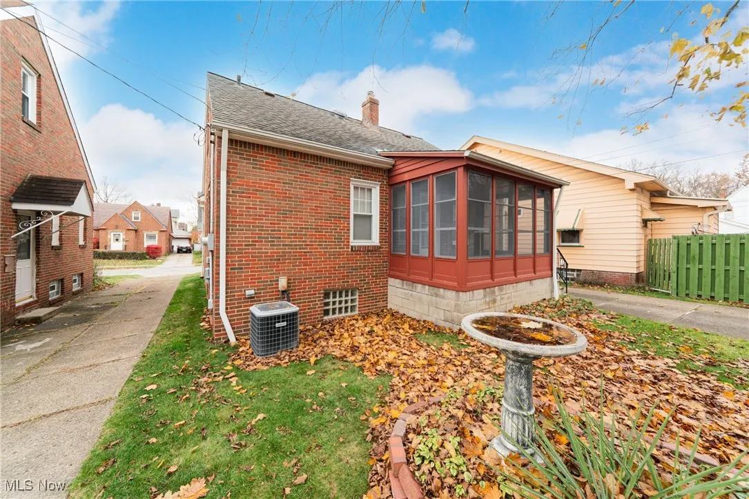 View of home's exterior with a chimney, a sunroom, roof with shingles, and brick siding