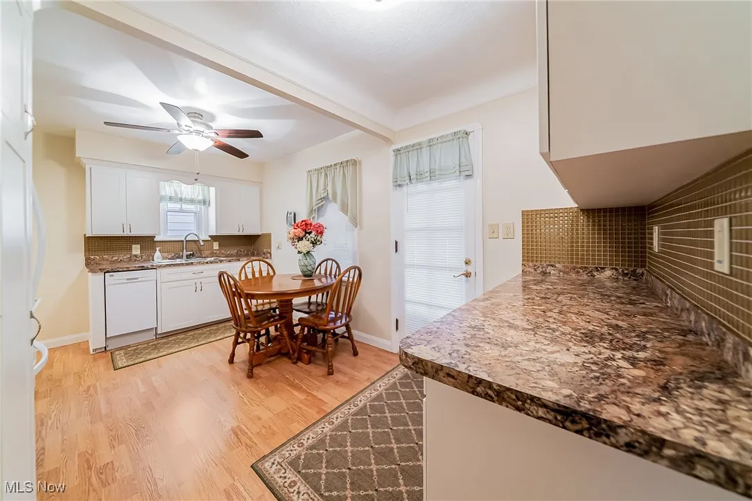 Kitchen featuring backsplash, light wood-style flooring, white appliances, beam ceiling, and white cabinets