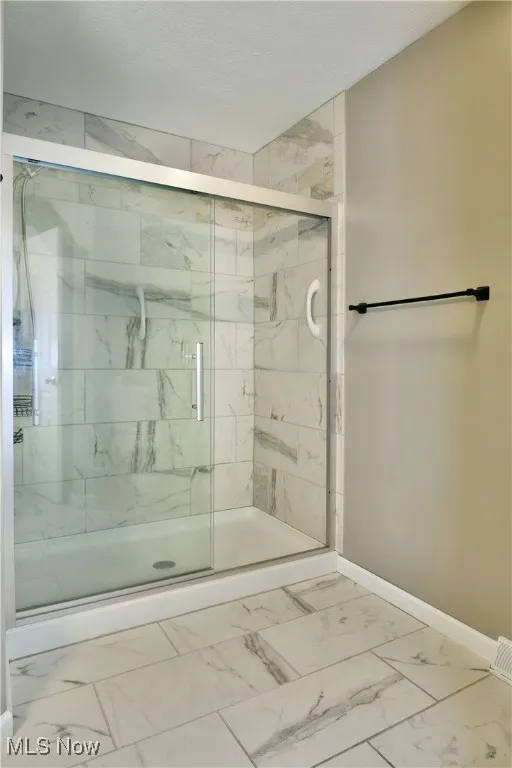 Full bathroom with marble finish flooring, a marble finish shower, and a textured ceiling