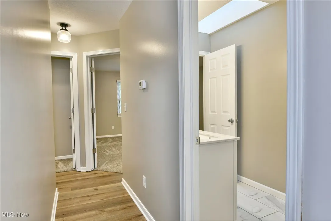 Corridor with a skylight and light wood-style flooring