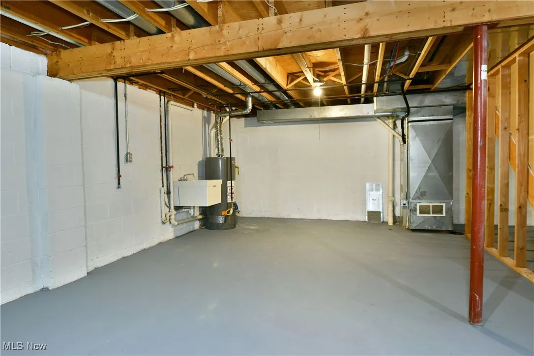 Unfinished below grade area featuring heating unit and gas water heater