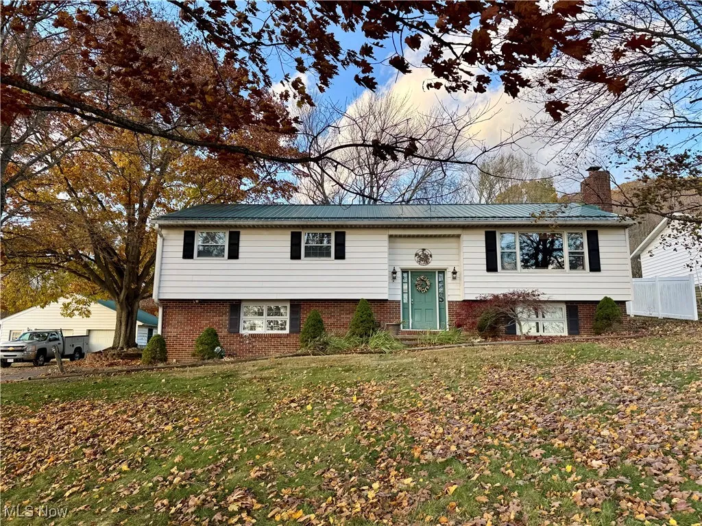 Split foyer home with brick siding, a chimney, a metal roof, and a detached garage