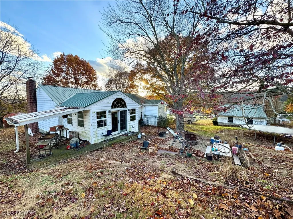 Rear view of house featuring a metal roof, a chimney, a trampoline, and a patio