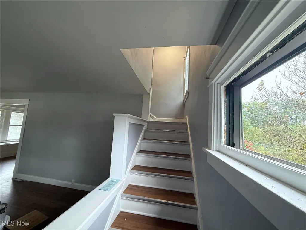 Stairway with wood finished floors and vaulted ceiling