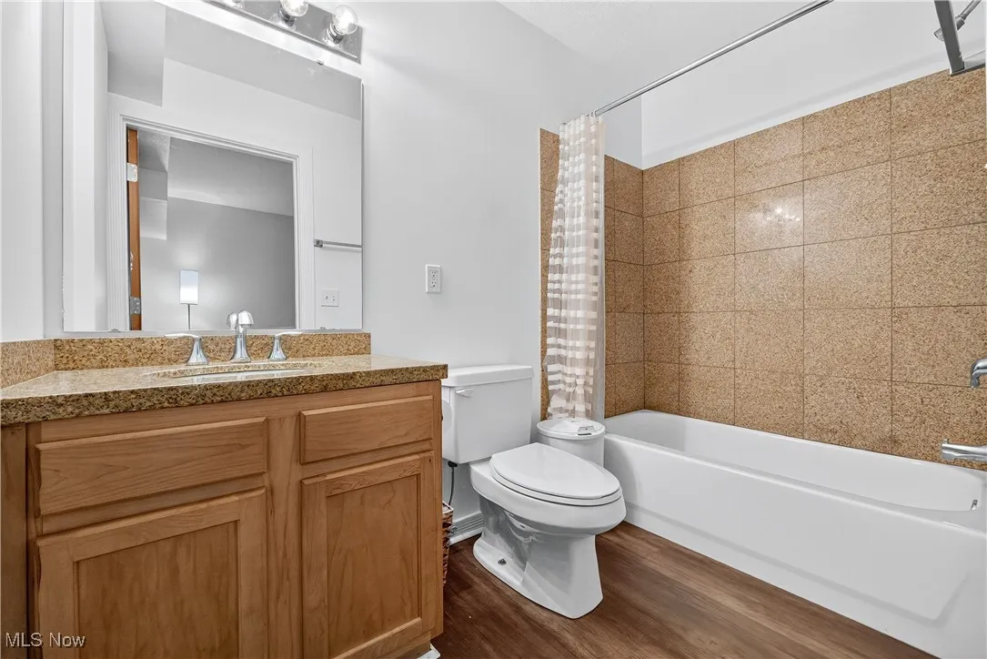 Full bathroom featuring dark wood finished floors, vanity, and shower / tub combo with curtain