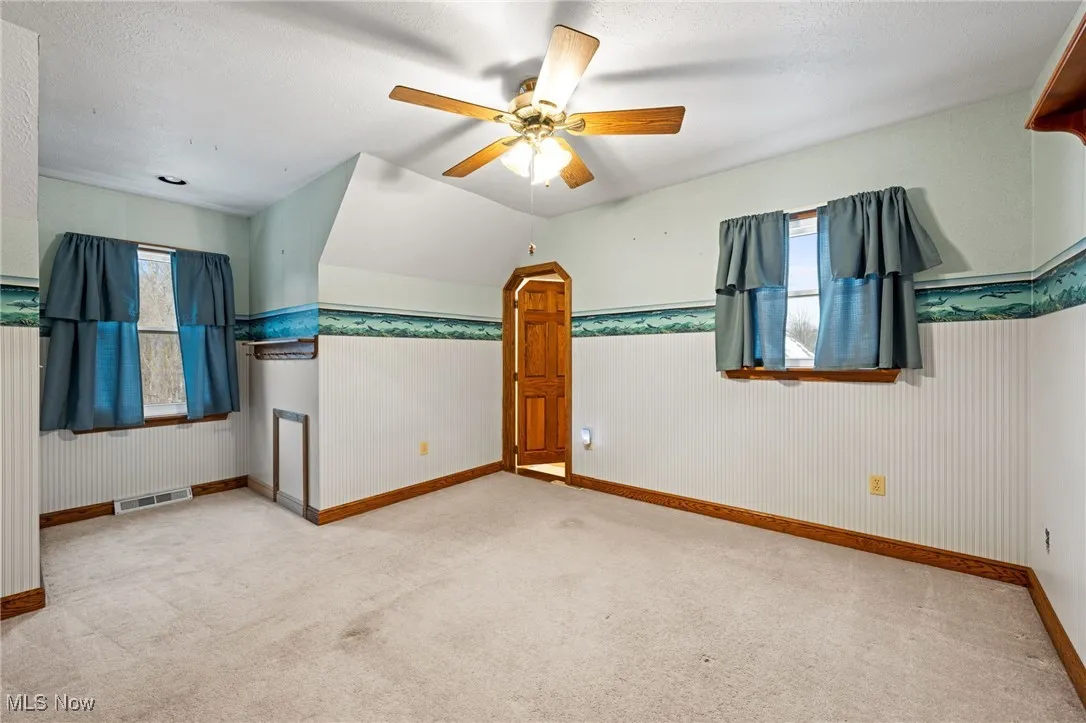 Bonus room with light carpet, ceiling fan, healthy amount of natural light, and a textured ceiling