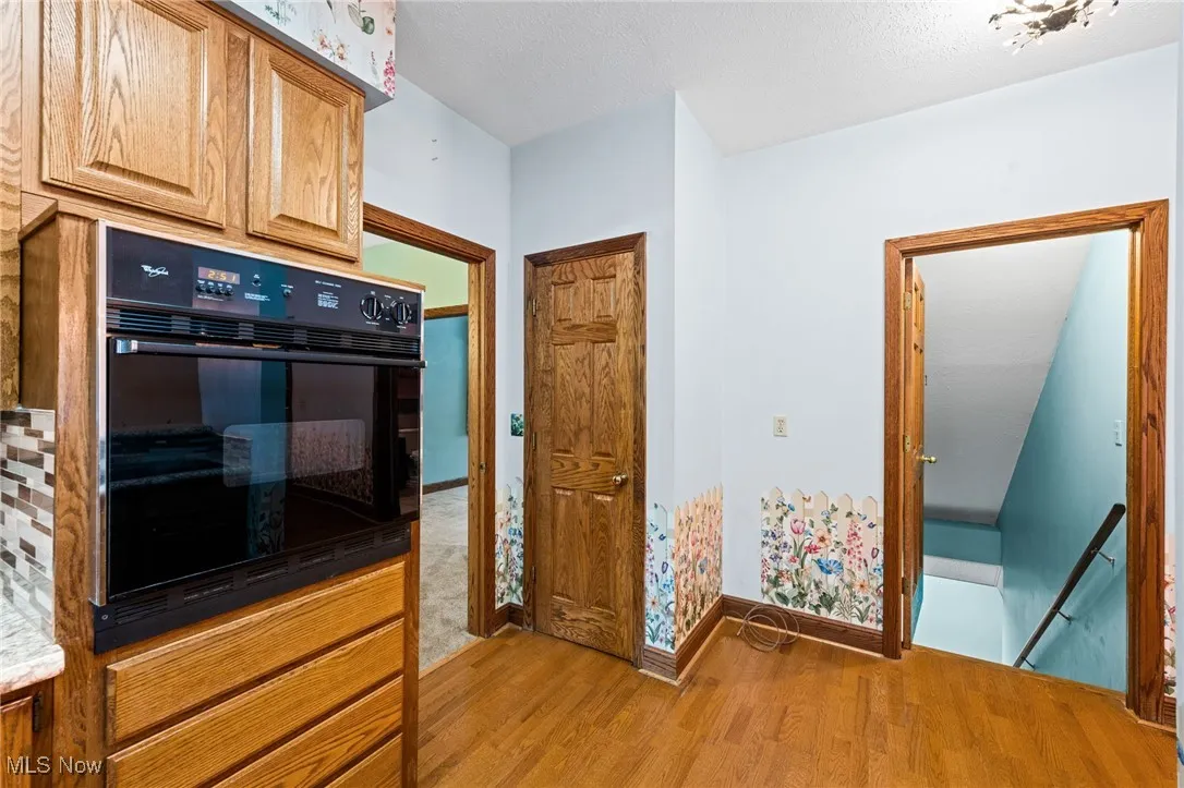 Kitchen with light wood-type flooring, oven, and a textured ceiling