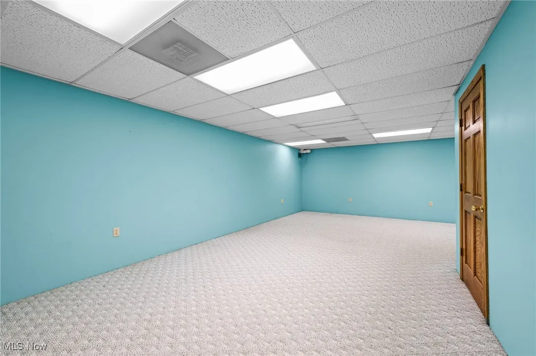 Carpeted empty room featuring a drop ceiling