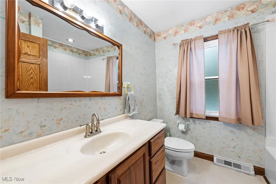 Bathroom featuring wallpapered walls, vanity, and curtained shower